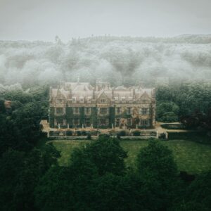 A large house surrounded by trees and fog