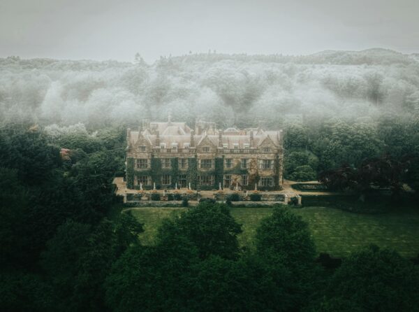 A large house surrounded by trees and fog